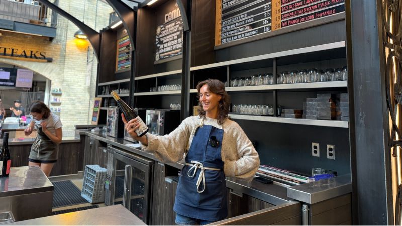 Félixe holding and smiling at a bottle of wine.